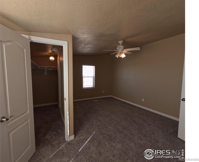 unfurnished bedroom with a textured ceiling, dark colored carpet, a closet, and baseboards