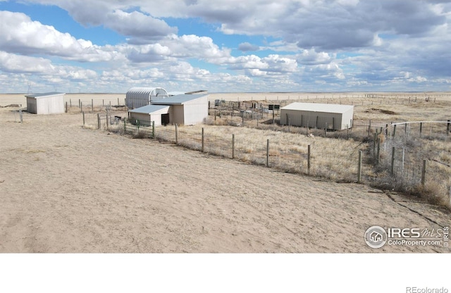 view of yard featuring an outbuilding, a rural view, and fence