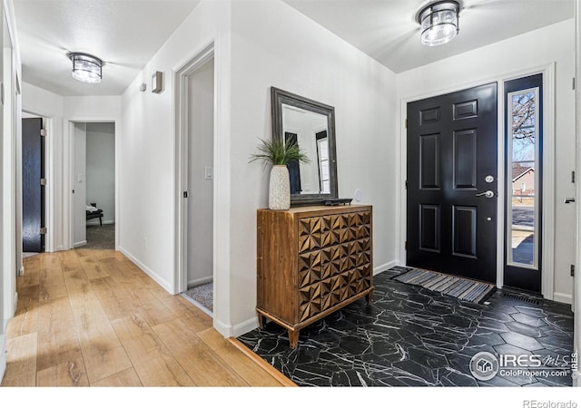 foyer featuring wood finished floors and baseboards