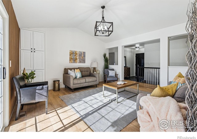 living area featuring light wood-style floors, lofted ceiling, and a notable chandelier