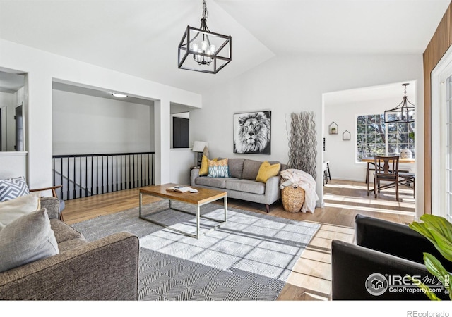 living room featuring a chandelier, wood finished floors, and lofted ceiling