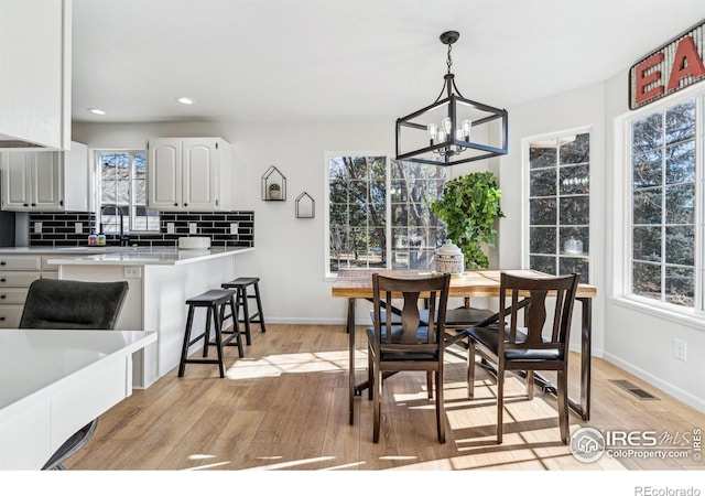 dining space with a wealth of natural light, visible vents, and light wood-style flooring