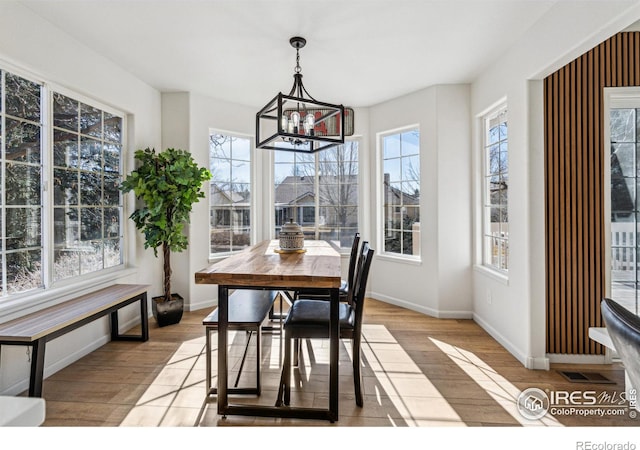 dining room with a chandelier, wood finished floors, visible vents, and baseboards