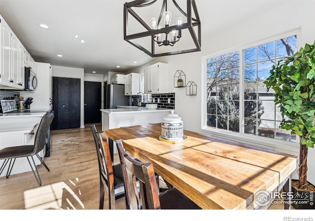 dining room with recessed lighting, light wood-style flooring, and an inviting chandelier