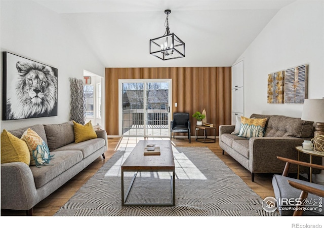 living area featuring an inviting chandelier, high vaulted ceiling, and wood finished floors