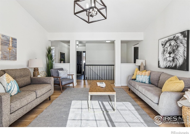 living area with vaulted ceiling, a notable chandelier, and wood finished floors