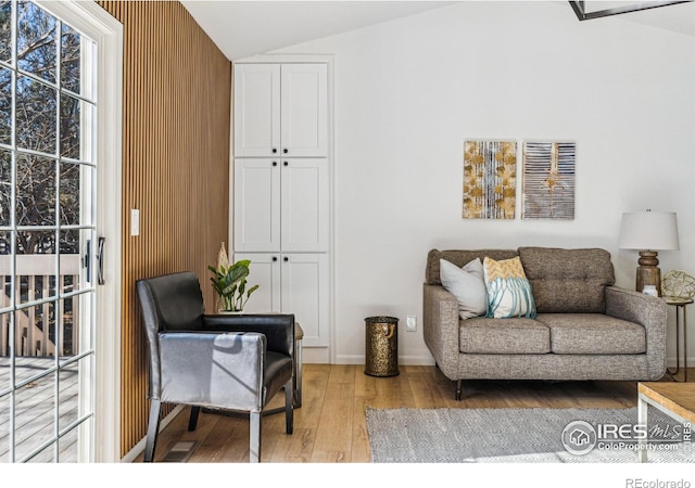 living area featuring lofted ceiling, baseboards, and wood finished floors