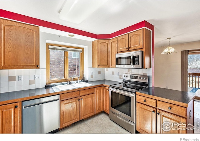 kitchen with appliances with stainless steel finishes, dark countertops, a sink, and backsplash