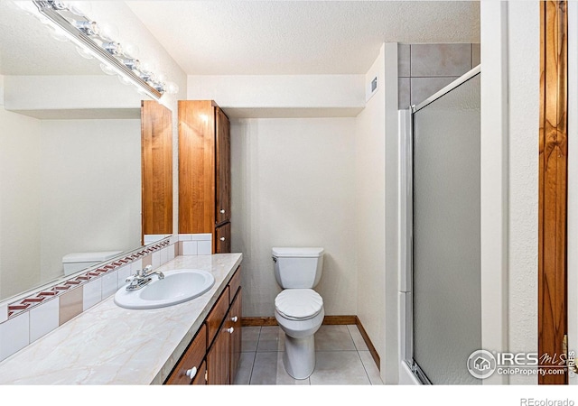 bathroom featuring a stall shower, toilet, tile patterned floors, a textured ceiling, and vanity