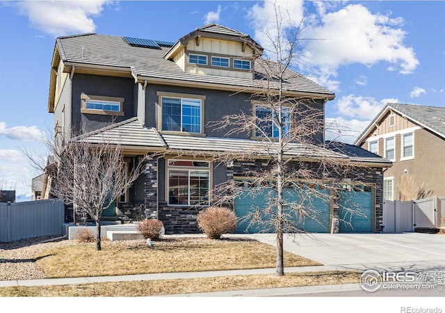 view of front of property with a tile roof, fence, concrete driveway, roof mounted solar panels, and stucco siding