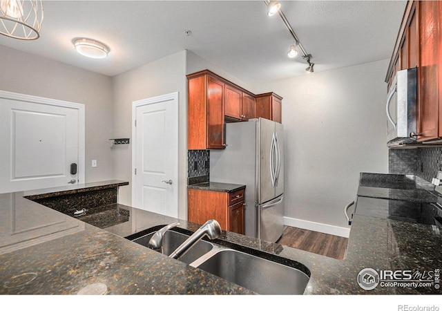 kitchen with stainless steel appliances, tasteful backsplash, a sink, and dark wood finished floors