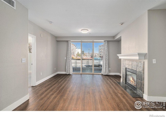 unfurnished living room featuring visible vents, a fireplace, baseboards, and dark wood-style flooring