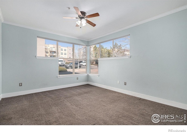 empty room featuring baseboards, dark colored carpet, and crown molding