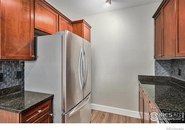 kitchen featuring dark stone countertops, freestanding refrigerator, baseboards, and wood finished floors