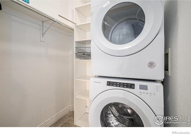 washroom featuring laundry area, stacked washing maching and dryer, baseboards, and tile patterned floors