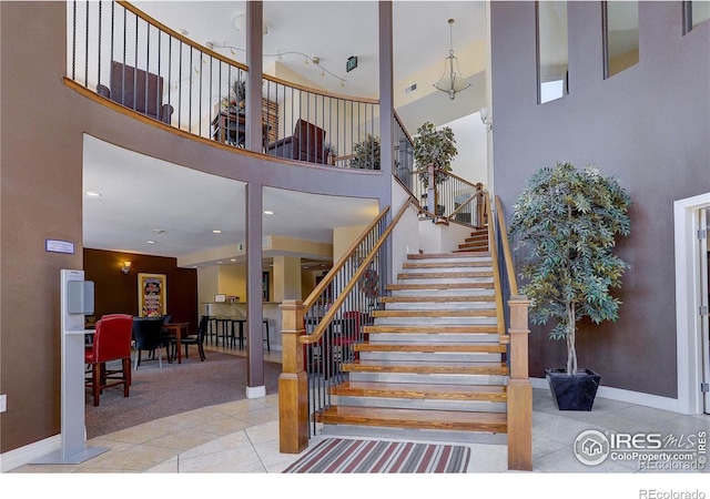 stairs with carpet flooring, tile patterned flooring, a towering ceiling, and baseboards