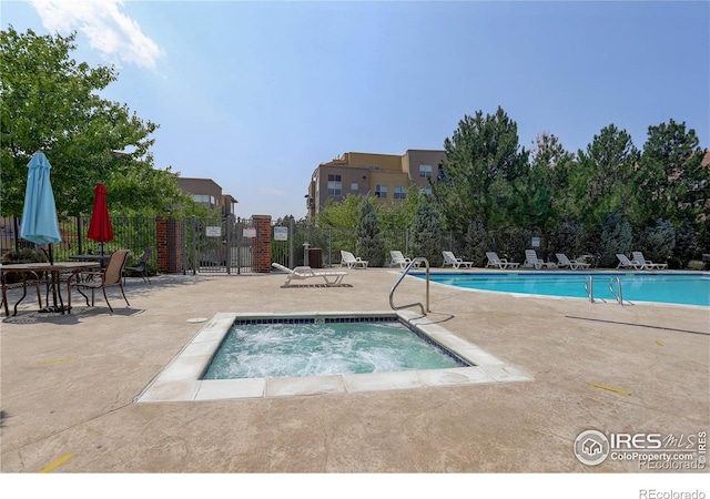 community pool featuring a patio, a community hot tub, and fence