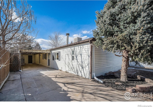 rear view of property with a carport and fence