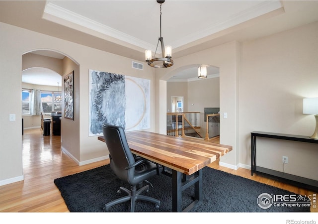 office space featuring visible vents, a tray ceiling, a chandelier, and wood finished floors