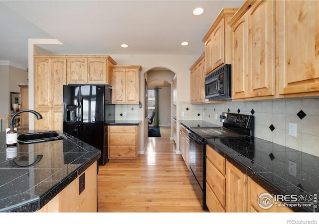 kitchen featuring tile counters, arched walkways, black appliances, light brown cabinets, and a sink