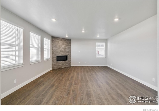 unfurnished living room with a fireplace, baseboards, dark wood finished floors, and recessed lighting