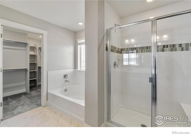 bathroom with a spacious closet, a shower stall, and a bath