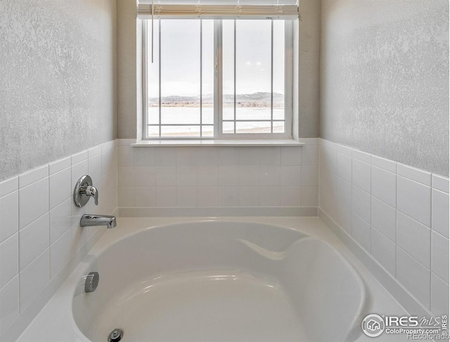 bathroom with a bath and a textured wall