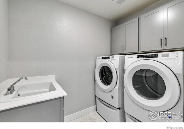 washroom featuring marble finish floor, cabinet space, washing machine and dryer, a sink, and baseboards