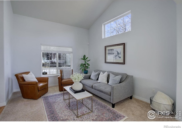 carpeted living area with high vaulted ceiling, plenty of natural light, and baseboards