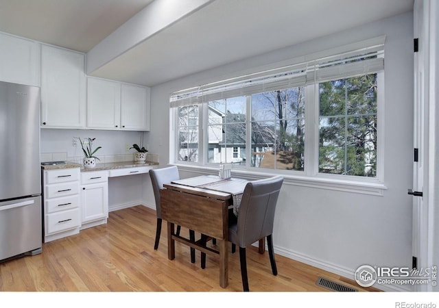 dining area with light wood-style flooring, visible vents, baseboards, and built in study area