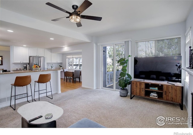 living room featuring light carpet, baseboards, a ceiling fan, and recessed lighting