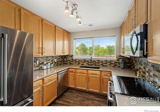 kitchen featuring a sink, light countertops, appliances with stainless steel finishes, backsplash, and dark wood-style floors