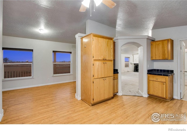 kitchen featuring light wood-style flooring, arched walkways, open floor plan, and a textured ceiling