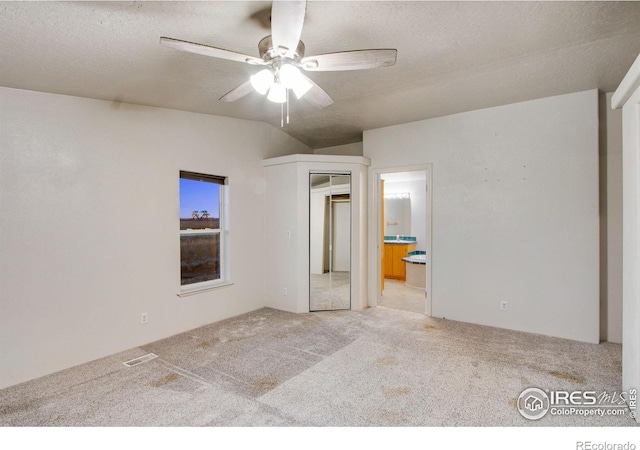 unfurnished bedroom with carpet, visible vents, a textured ceiling, and ensuite bathroom