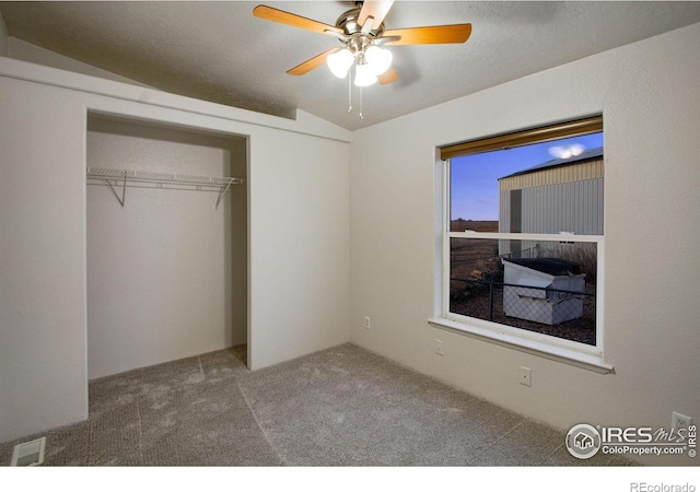 unfurnished bedroom featuring carpet floors, a closet, visible vents, a ceiling fan, and vaulted ceiling