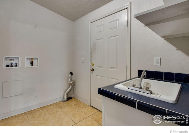 laundry room with laundry area, light tile patterned floors, a textured ceiling, washer hookup, and a sink