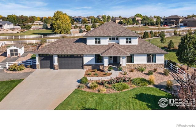 view of front facade featuring stone siding, fence, an attached garage, and stucco siding