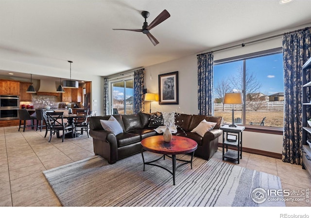 living room featuring a ceiling fan, light tile patterned flooring, and baseboards