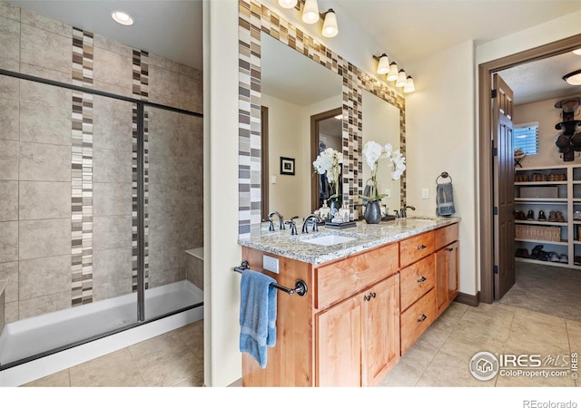 full bathroom featuring double vanity, a shower stall, a sink, and tile patterned floors