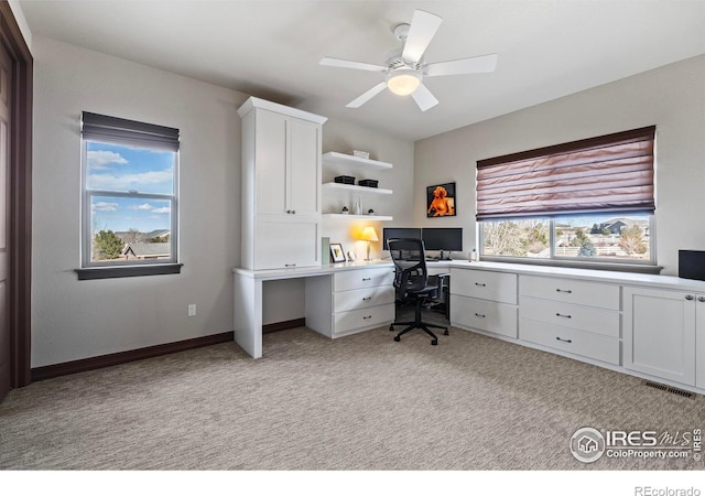 office space featuring baseboards, a ceiling fan, a wealth of natural light, and light colored carpet