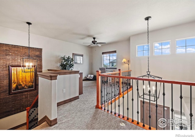 interior space with ceiling fan with notable chandelier, carpet flooring, and baseboards