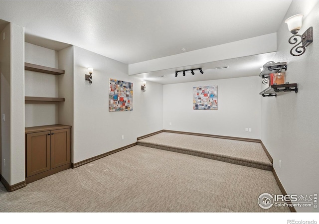 spare room featuring visible vents, baseboards, track lighting, and light colored carpet