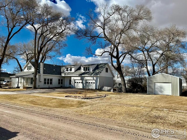 view of front of property with a garage, a front lawn, and an outbuilding