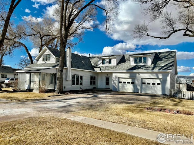 view of front facade with driveway, an attached garage, and fence