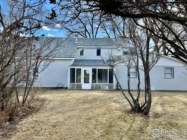 back of house featuring a sunroom, a yard, and roof with shingles