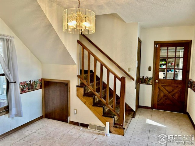 entrance foyer with a textured ceiling, stairway, tile patterned flooring, and visible vents