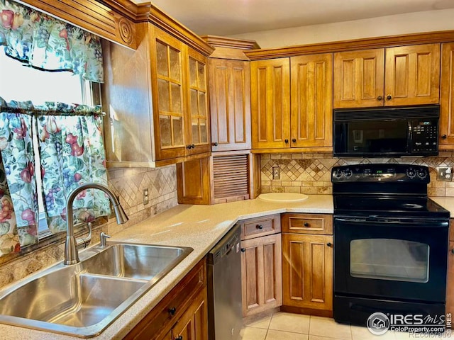 kitchen featuring light tile patterned floors, brown cabinetry, light countertops, black appliances, and a sink