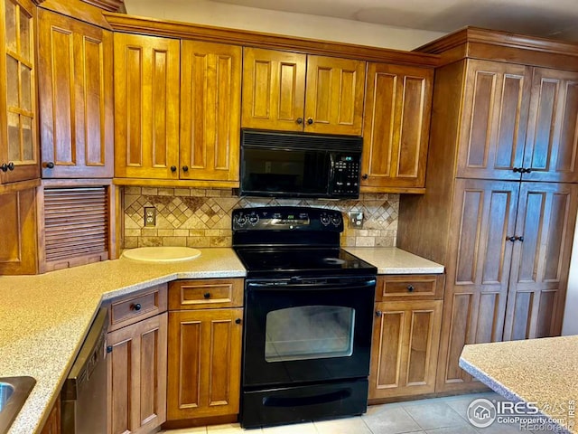 kitchen featuring brown cabinetry, decorative backsplash, black appliances, and light tile patterned floors