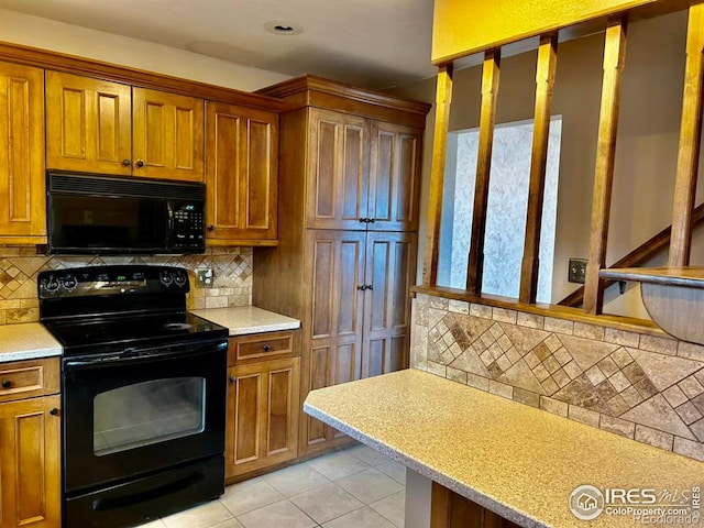 kitchen featuring black appliances, light tile patterned flooring, light countertops, and brown cabinets