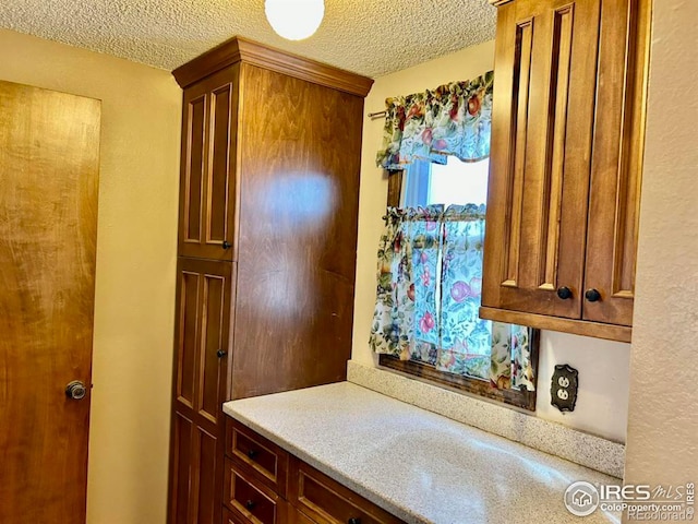 kitchen featuring brown cabinetry, light countertops, and a textured ceiling